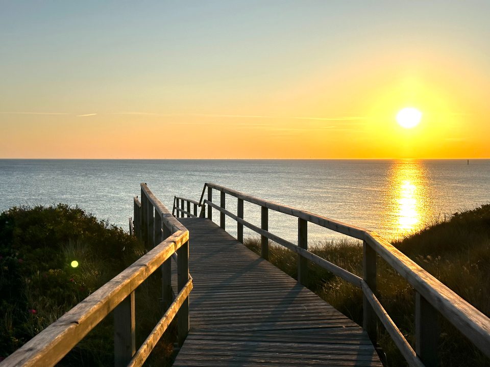A wooden pier reaching toward the sea at sunset